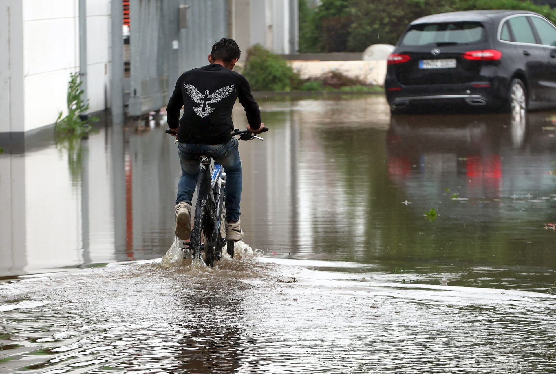 Bayern, Babenhausen: Ein Radfahrer fährt über eine überflutete Straße.