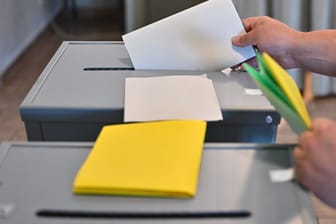 Eine Person steckt seinen Wahlzettel zu Europawahl in eine Wahlurne