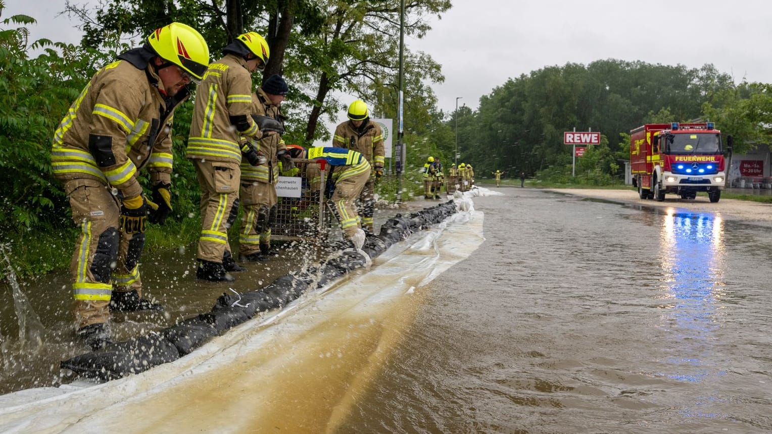Feuerwehrleute arbeiten an einer von der Günz überfluteten Straße in Ichenhausen.