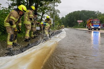Feuerwehrleute arbeiten an einer von der Günz überfluteten Straße in Ichenhausen.
