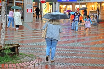 Menschen laufen bei Regen durch Essen (Archivbild): Am Montag und Dienstag sollten die Bewohner von NRW am besten immer einen Schirm zur Hand haben.
