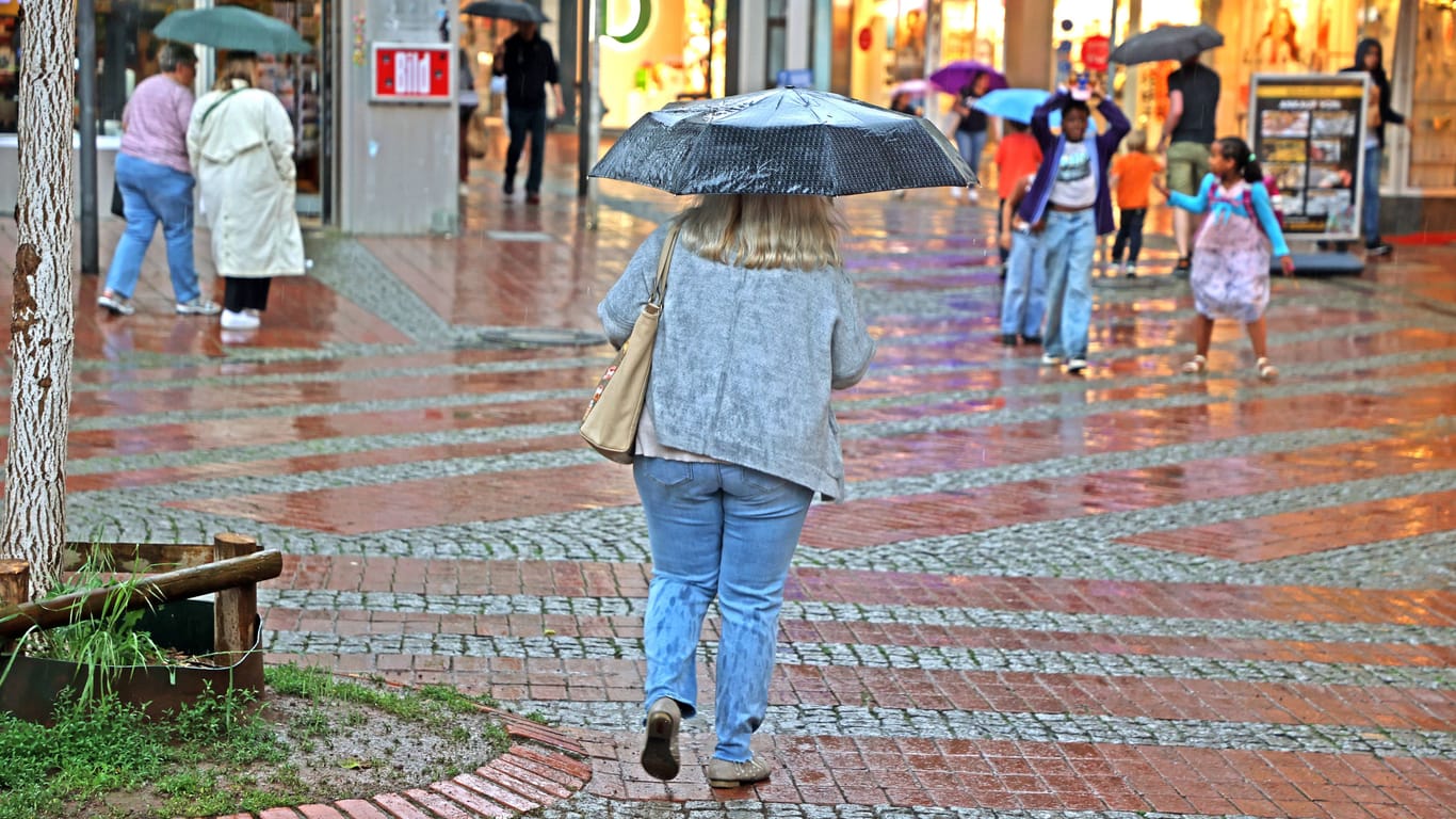 Menschen laufen bei Regen durch Essen (Archivbild): Am Montag und Dienstag sollten die Bewohner von NRW am besten immer einen Schirm zur Hand haben.