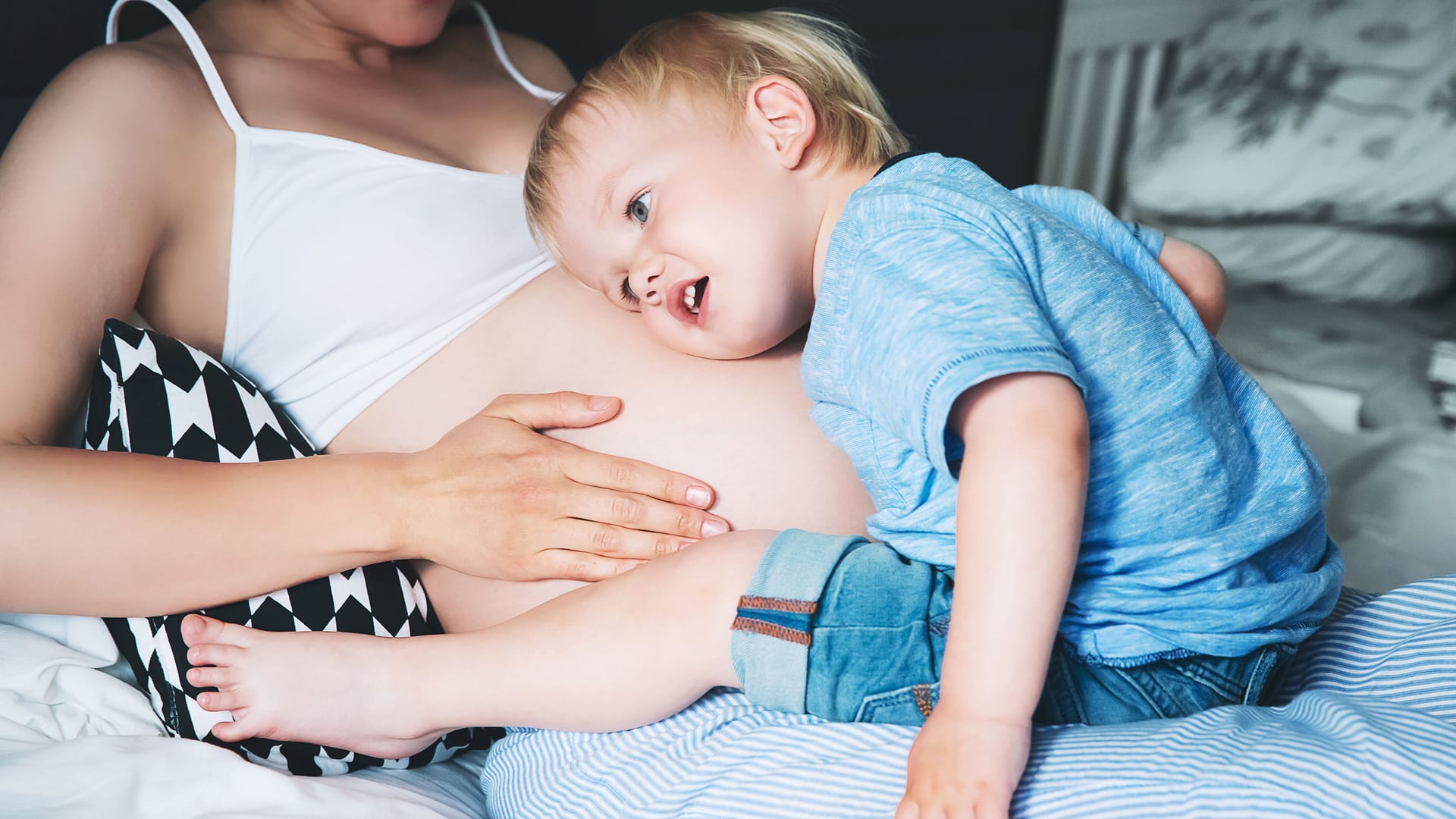 Ein Kind legt seinen Kopf auf den Bauch seiner schwangeren Mutter