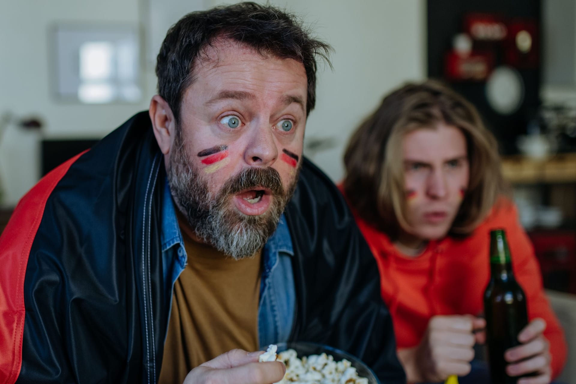 Nervous football fans friends staring at TV and watching football match at home