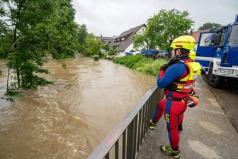 Ein Retter der DLRG blickt auf den angeschwollenen Fluss in Neu-Ulm: Im nahen Wald wurde eine junge Frau nach 52 Stunden lebend und unverletzt gefunden.