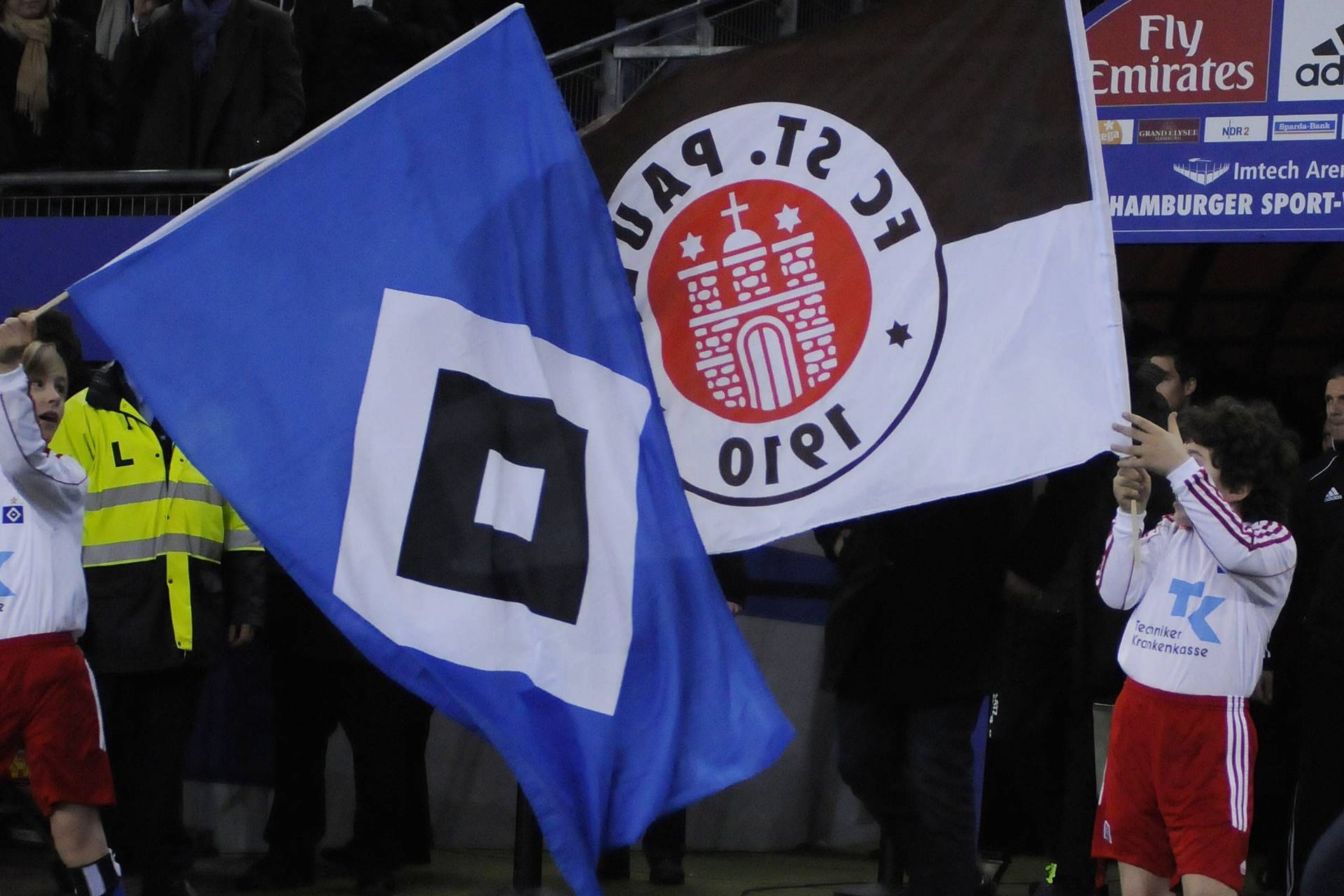 Kinder halten eine HSV- und eine St. Pauli-Fahne hoch (Archivbild): Die Stadtrivale machen gemeinsame Sache gegen Rechtsextremismus.