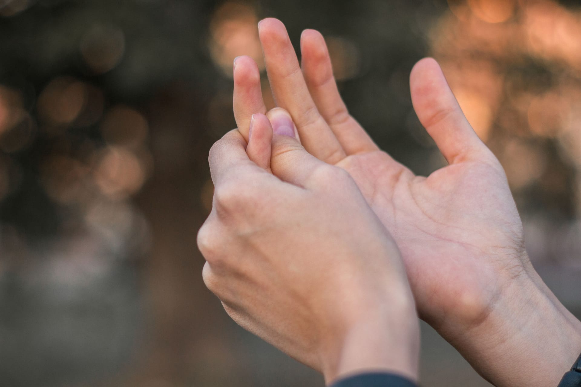 Jemand umfasst einen schmerzenden Finger: Geht der Schnappfinger mit Schmerzen einher, können Schmerzmittel helfen.