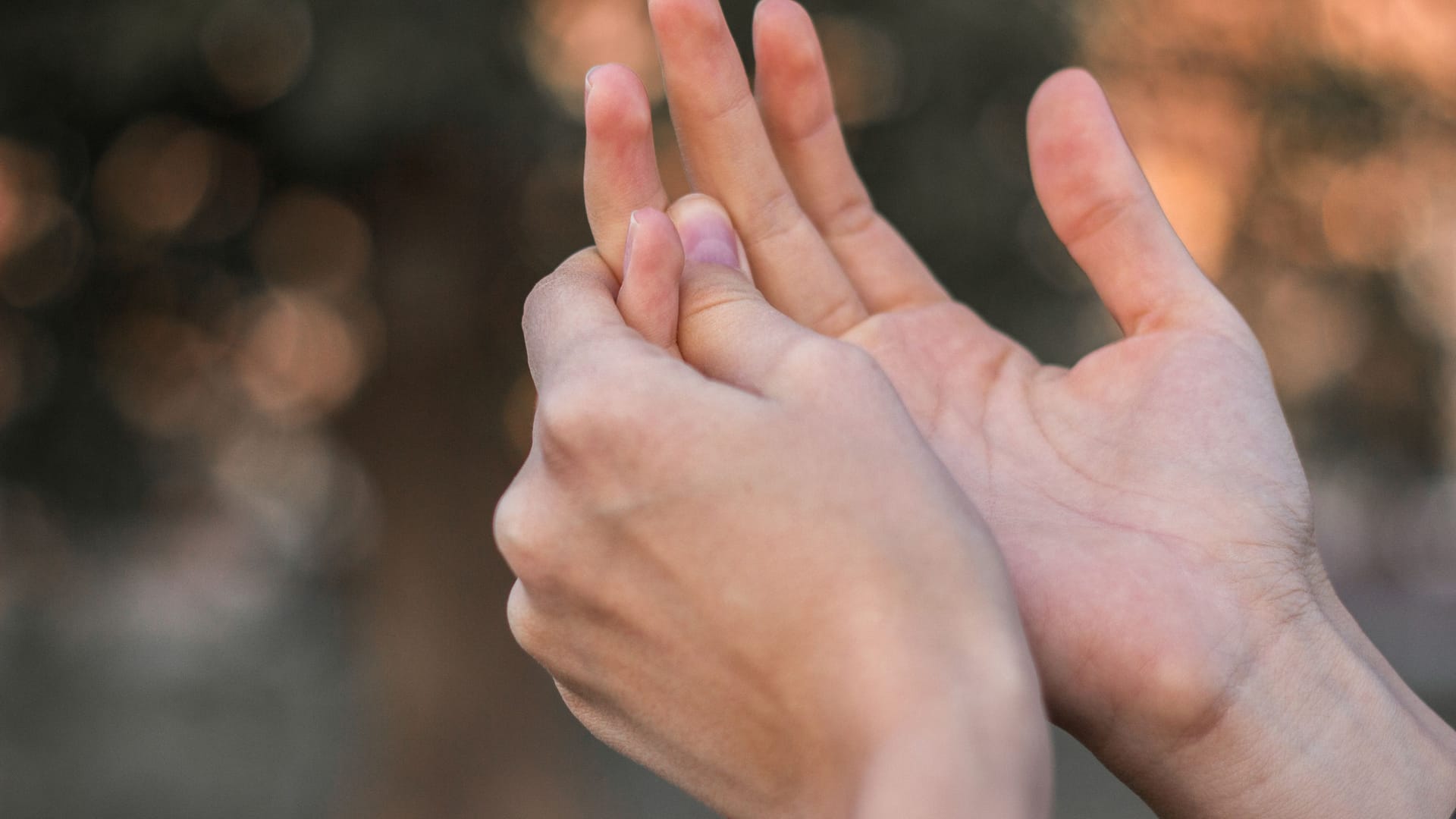 Jemand umfasst einen schmerzenden Finger: Geht der Schnappfinger mit Schmerzen einher, können Schmerzmittel helfen.