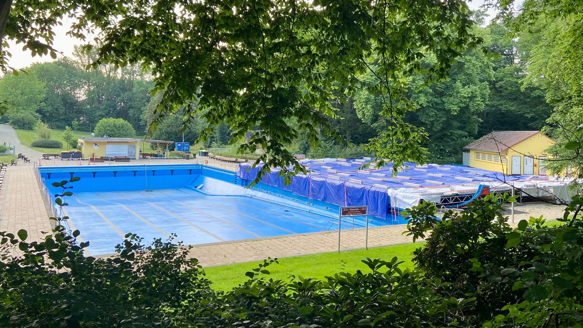 Die große Plane deckt das Nichtschwimmerbecken zurzeit noch komplett ab, auch im Schwimmerbecken fehlt noch das Wasser.