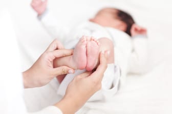 Eine Ärztin untersucht die Füße eines Babys.