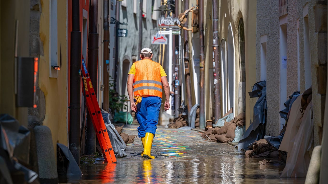 Bayern, Passau: Ein Helfer geht, nachdem das Hochwasser der Donau etwas zurückgegangen ist, durch eine Gasse mit Sandsäcken vor den Häusern. Die Schäden sind enorm.