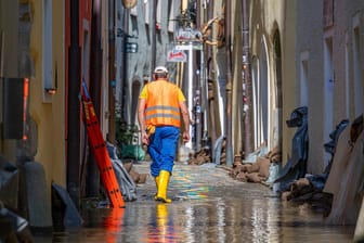 Bayern, Passau: Ein Helfer geht, nachdem das Hochwasser der Donau etwas zurückgegangen ist, durch eine Gasse mit Sandsäcken vor den Häusern. Die Schäden sind enorm.
