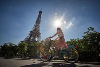 Eine Frau radelt vor dem Eiffelturm (Archivbild): In Paris werden Autos immer mehr aus dem Zentrum der Stadt verbannt.