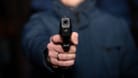 Ein Mann hält eine Pistole in der Hand (Symbolbild): Die Polizei hofft, dem Täter durch Videoaufnahmen auf die Spur zu kommen.