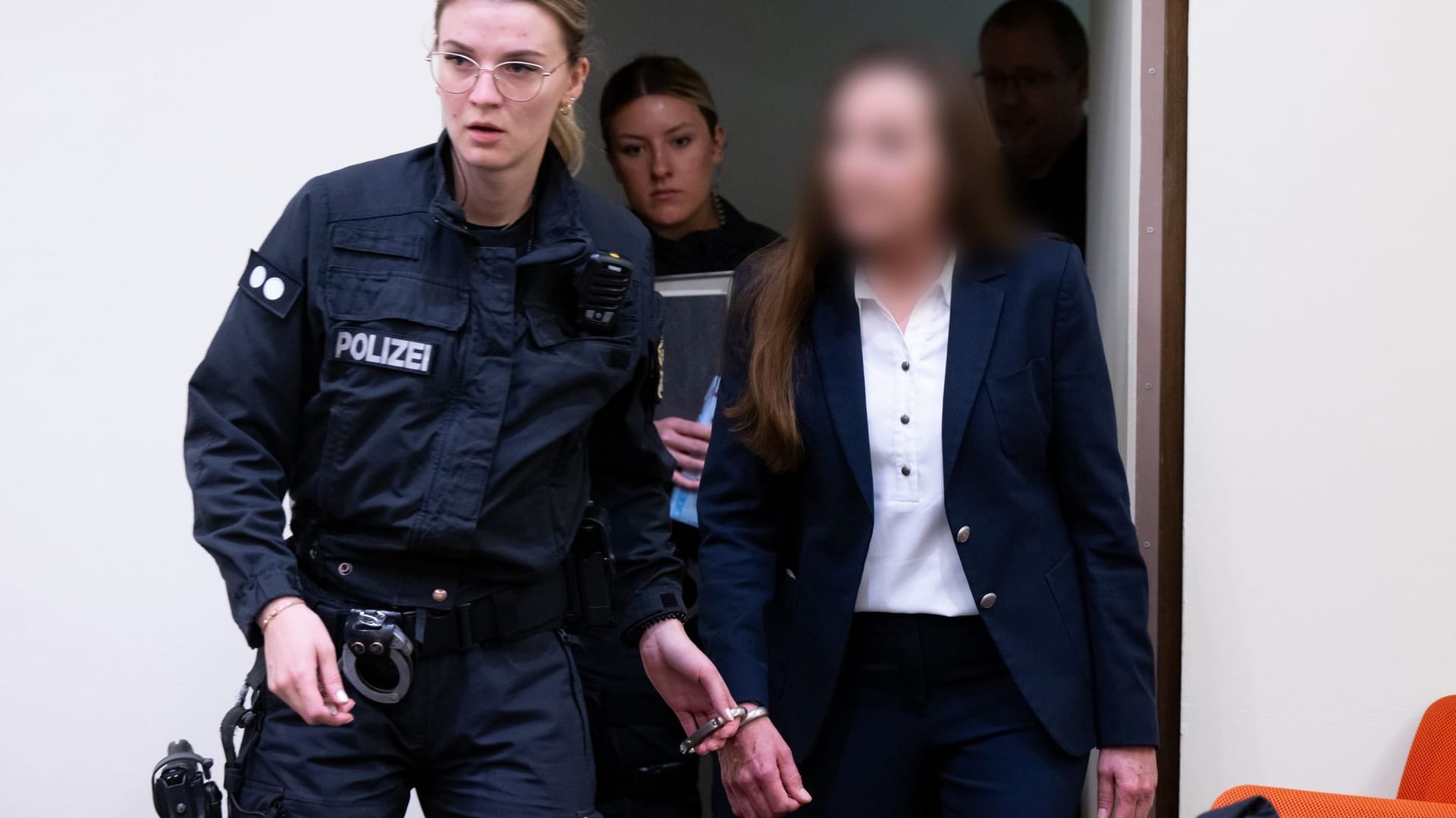 Eine wegen Mitgliedschaft in einer terroristischen Vereinigung angeklagte Frau wird im Oberlandesgericht in den Gerichtssaal des Oberlandesgerichts München geführt.