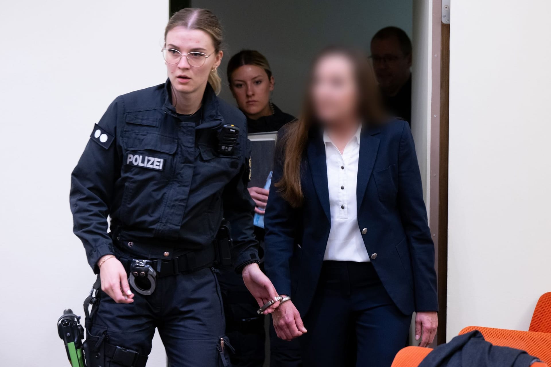 Eine wegen Mitgliedschaft in einer terroristischen Vereinigung angeklagte Frau wird im Oberlandesgericht in den Gerichtssaal des Oberlandesgerichts München geführt.