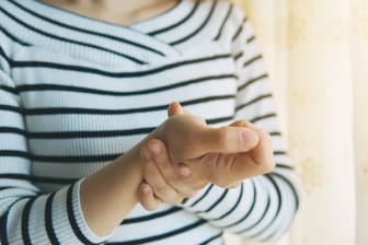 Frau mit Handbeschwerden: Ein Schnappfinger am Daumen kann den Alltag beeinträchtigen.
