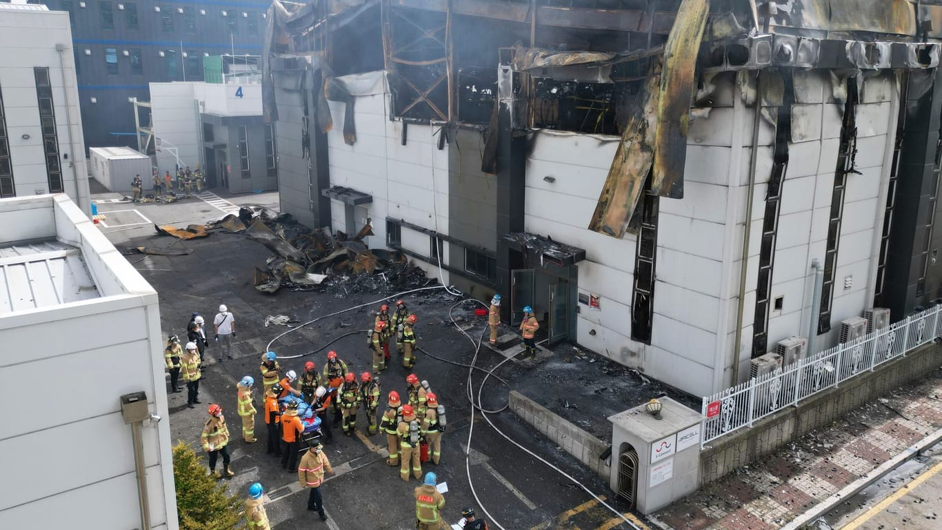 Feuerwehrleute vor einer verbrannten Batteriefabrik in Südkorea.