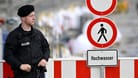 Polizist vor einem Hochwasserwarnschild (Symbolbild): Der Hochwasserschutz in Bayern hinkt seit Jahren den selbstgesteckten Zielen hinterher.