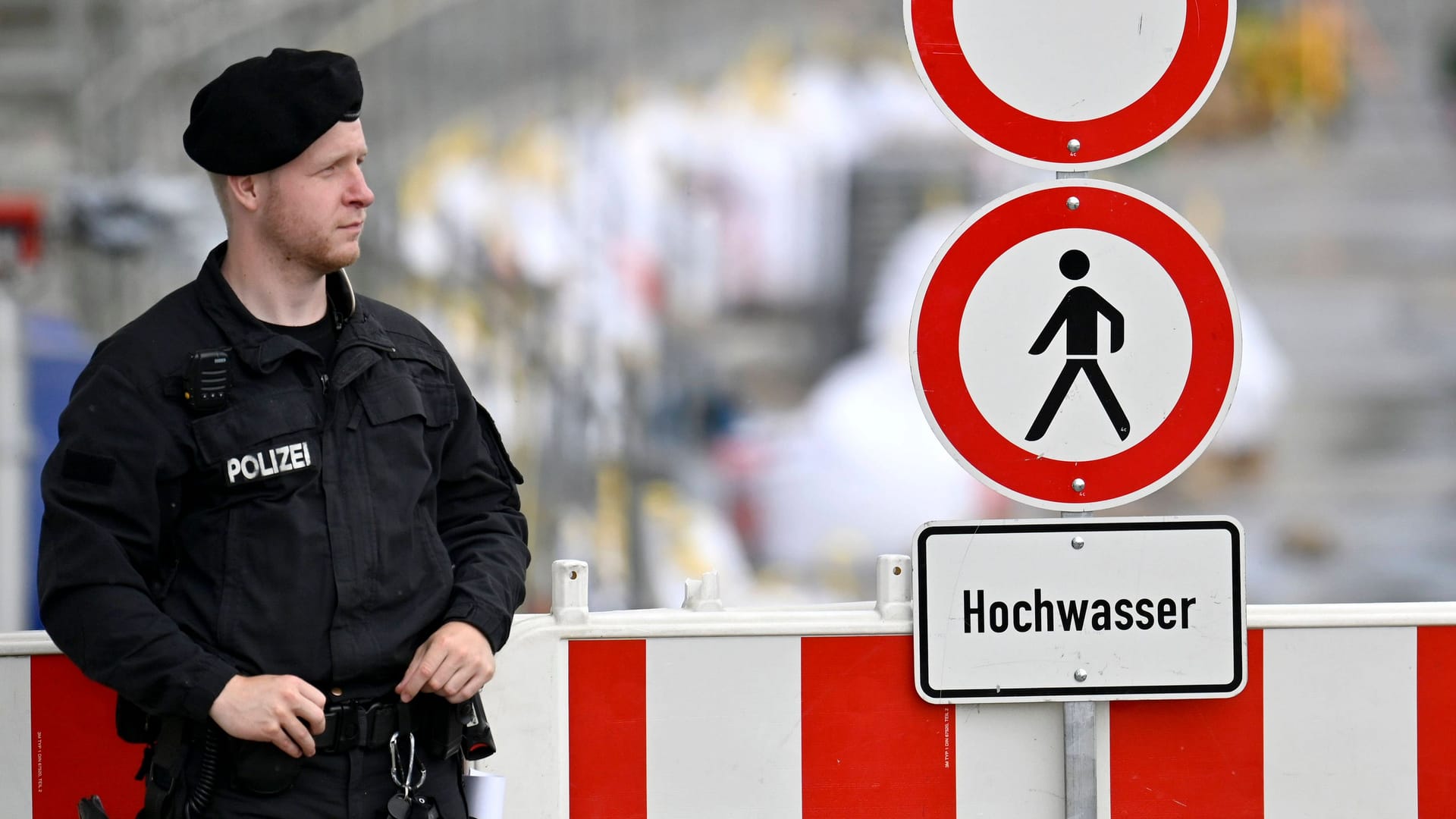 Polizist vor einem Hochwasserwarnschild (Symbolbild): Der Hochwasserschutz in Bayern hinkt seit Jahren den selbstgesteckten Zielen hinterher.