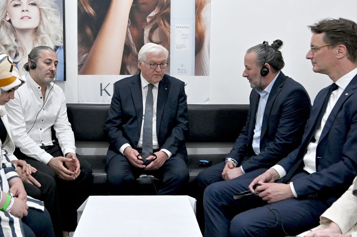 Bundespräsident Frank-Walter Steinmeier (M) und Hendrik Wüst (CDU, r), Ministerpräsident von Nordrhein-Westfalen, sprechen mit Hasan Yildirim (hinten l) und Özcan Yildirim (2.v.r) in deren Friseurgeschäft. Vor dem Laden hatten Rechtsterroristen eine Nagelbombe gezündet.