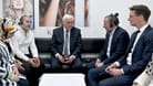 Bundespräsident Frank-Walter Steinmeier (M) und Hendrik Wüst (CDU, r), Ministerpräsident von Nordrhein-Westfalen, sprechen mit Hasan Yildirim (hinten l) und Özcan Yildirim (2.v.r) in deren Friseurgeschäft. Vor dem Laden hatten Rechtsterroristen eine Nagelbombe gezündet.
