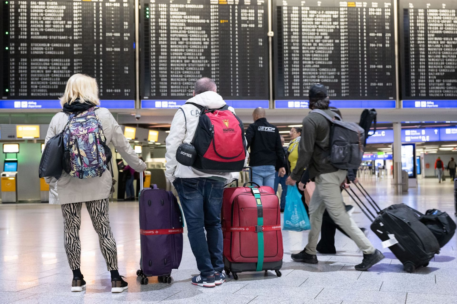 Passagiere stehen mit ihren Koffern vor einer Anzeigetafel im Flughafen (Symbolbild): FTI storniert alle Reisen.