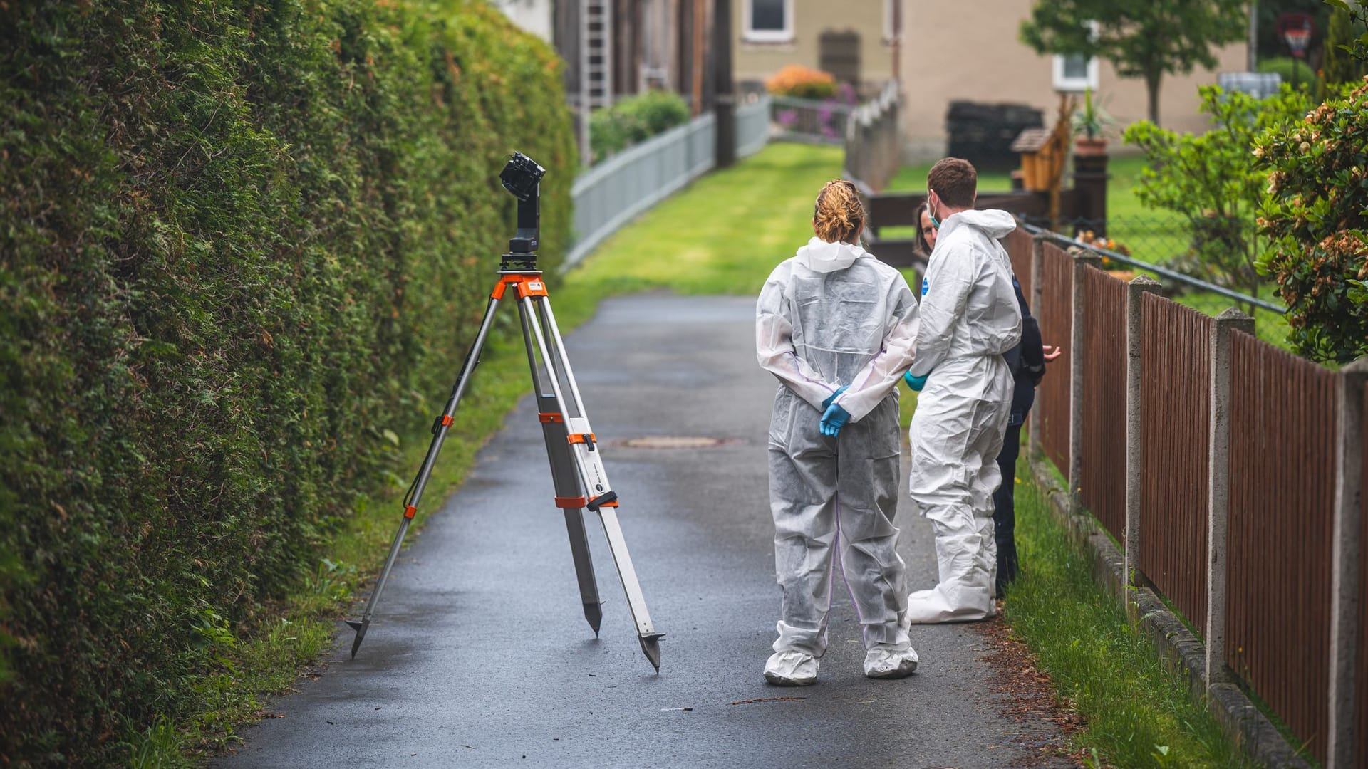 Polizeibeamte stehen an einem Tatort auf der Straße. In einem nahe gelegenen Haus war es zu einem Gewaltverbrechen mit drei Toten gekommen.