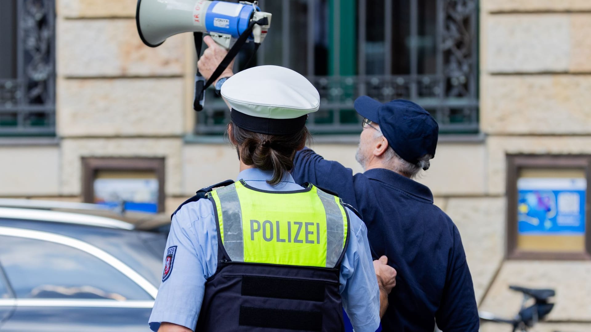 Düsseldorf: Ein Störer wird von einem Polizisten abgeführt.