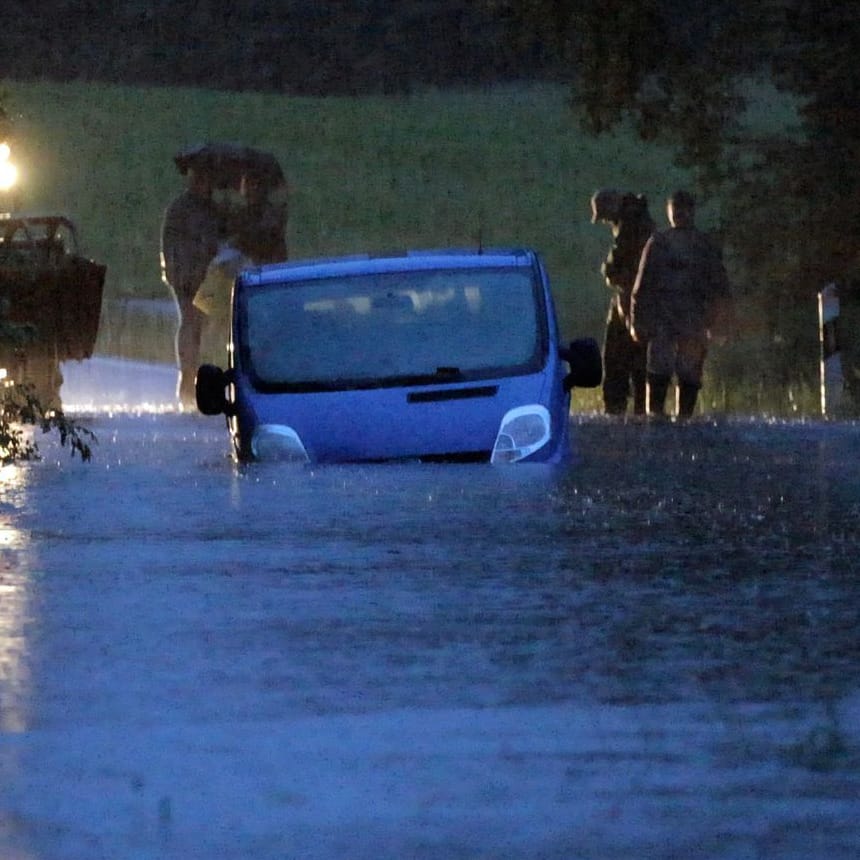 Ein Fahrzeug steht von Wasser umgeben auf einer überfluteten Straße am Bodensee.