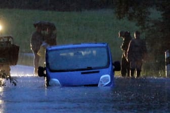 Ein Fahrzeug steht von Wasser umgeben auf einer überfluteten Straße am Bodensee.