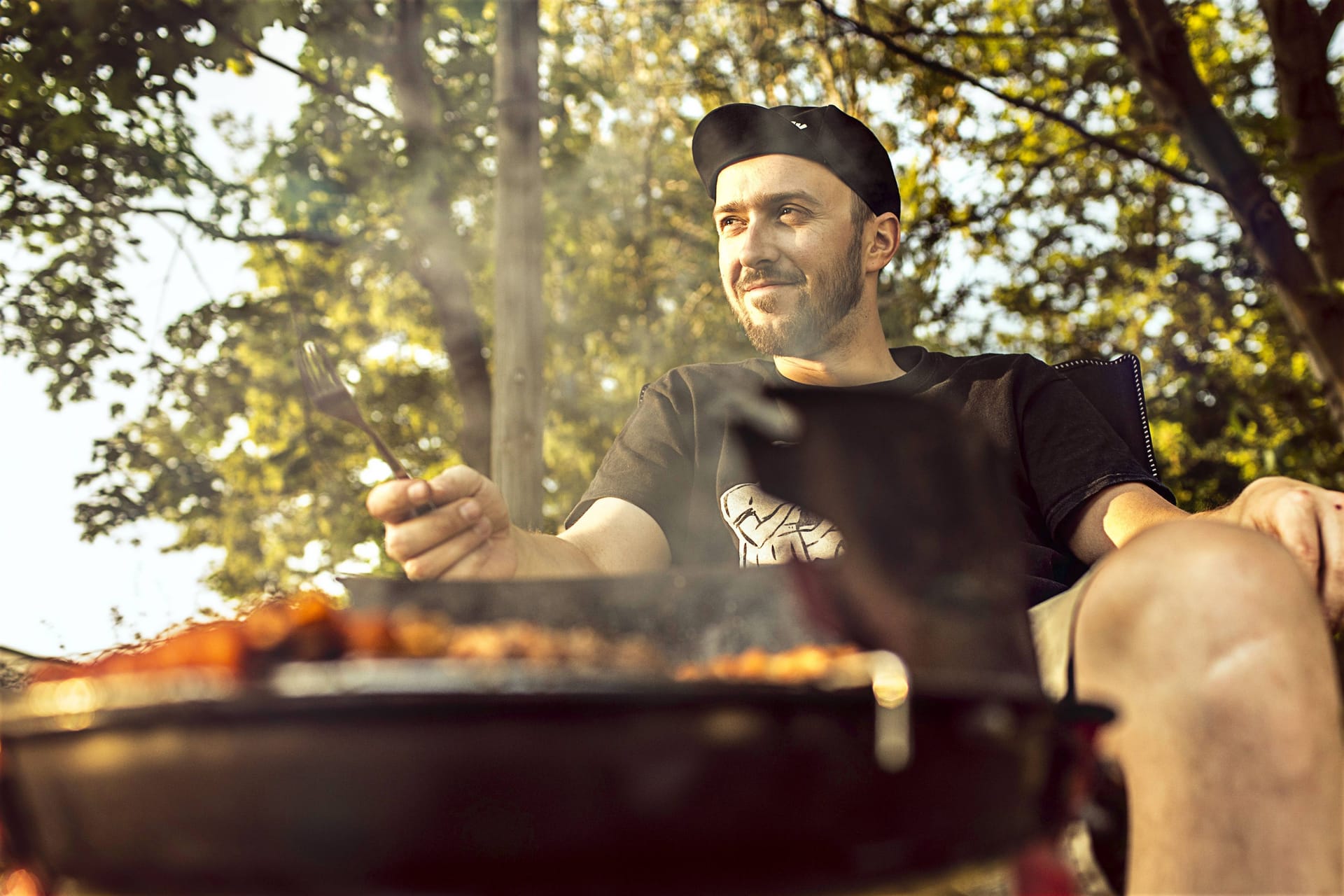 Ein Mann sitzt vor einem Grill in Hannover: Wer draußen grillen möchte, sollte sich an die Vorgaben halten.