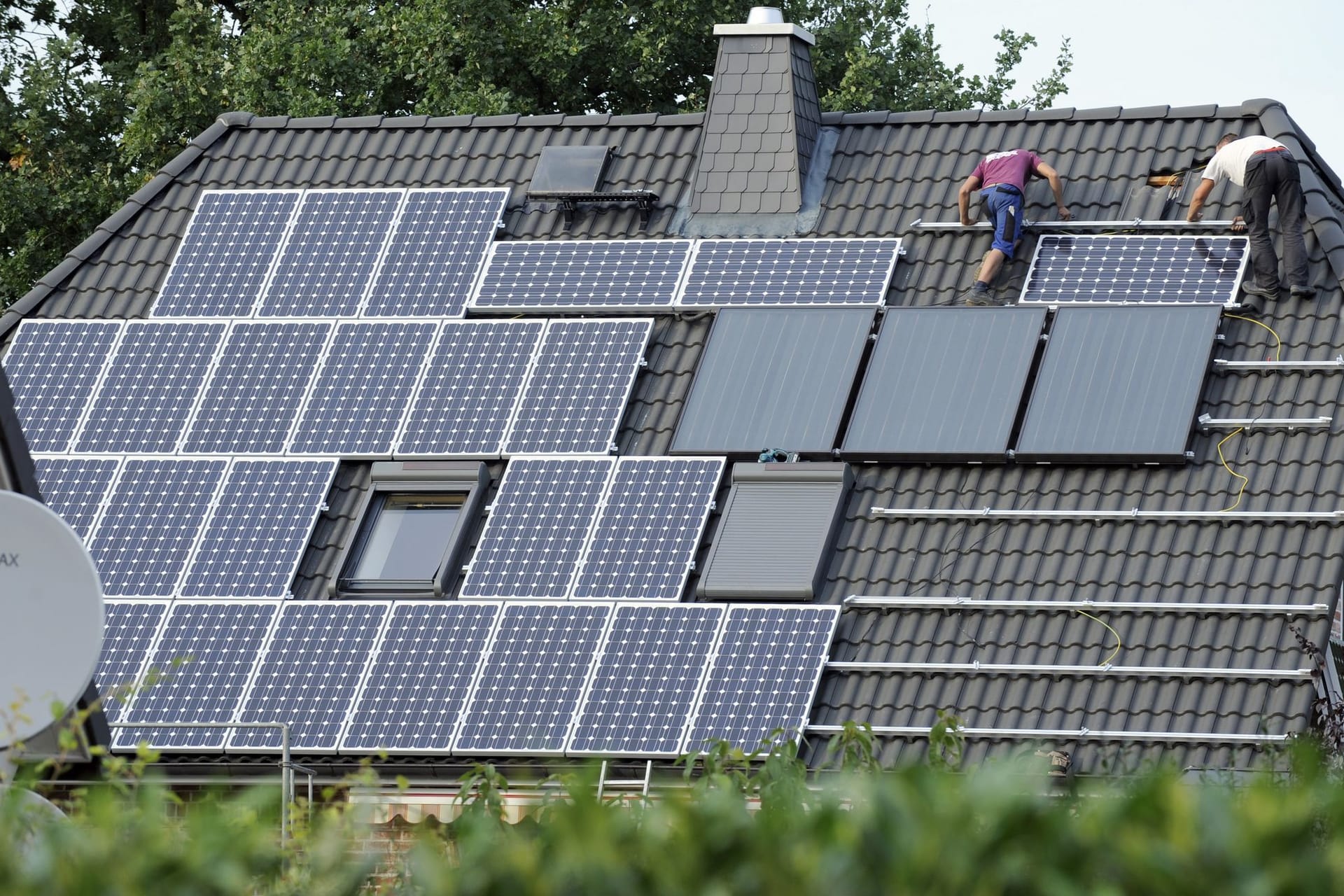 Monteure installieren eine PV-Anlage auf einem Hausdach