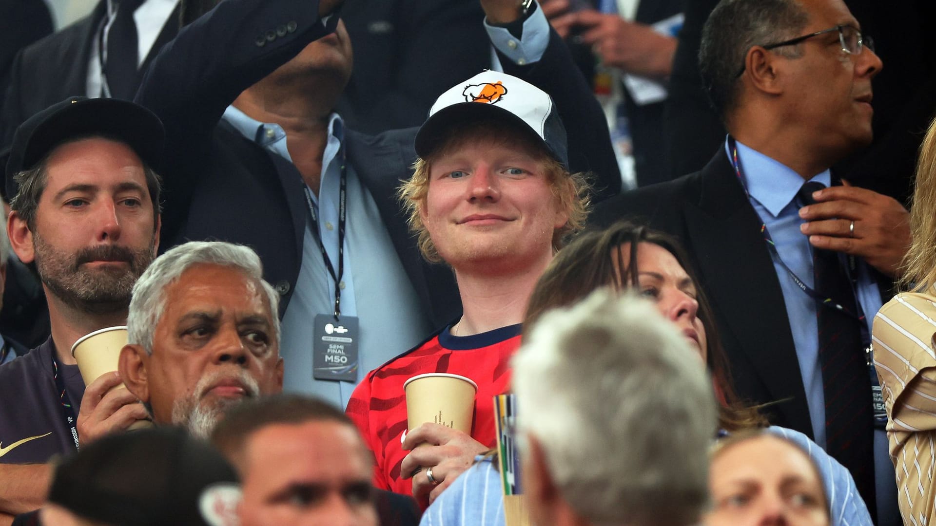 Ed Sheeran (M) steht vor dem Spielbeginn auf der Tribüne in Dortmund.