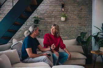 Ein Mann und eine Frau sitzen angespannt auf einem Sofa