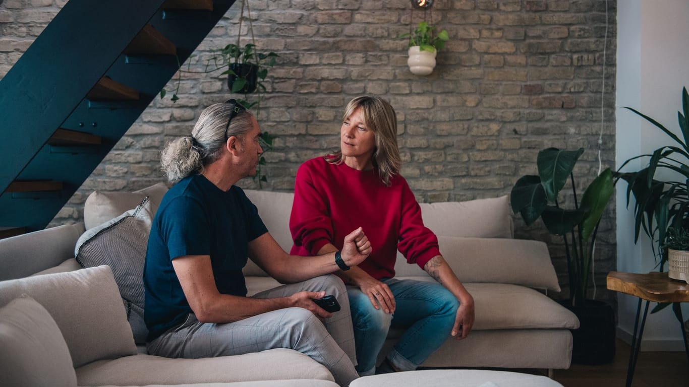 Ein Mann und eine Frau sitzen angespannt auf einem Sofa