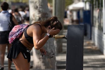 Eine Frau sucht Erfrischung an einem Wasserbrunnen in der Stadtmitte. Nach Angaben der staatlichen meteorologischen Agentur Aemet werden in Barcelona hohe Temperaturen erwartet.