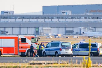 Klimakleber auf dem Rollfeld am Frankfurter Flughafen, umkreist von Polizei und Feuerwehr.