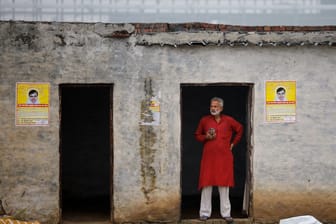 Ein Mann steht an einem Gebäude mit Postern des Predigers Surajpal, auch bekannt als "Bhole Baba", in der Nähe des Ortes, an dem die Massenpanik 120 Menschen das Leben kostete.