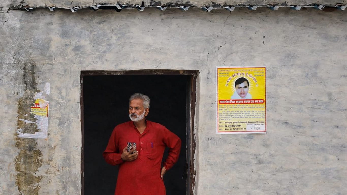 Ein Mann steht an einem Gebäude mit Postern des Predigers Surajpal, auch bekannt als "Bhole Baba", in der Nähe des Ortes, an dem die Massenpanik 120 Menschen das Leben kostete.