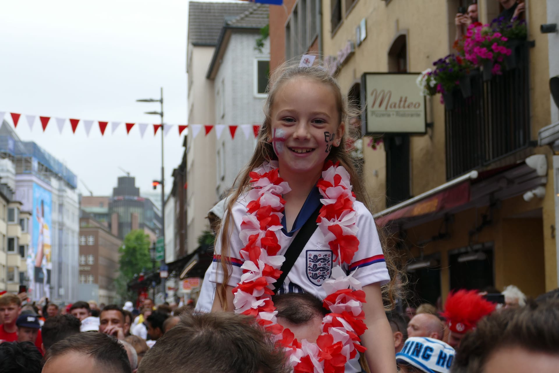 Englische Fans findet man am Samstagüberall in Düsseldorf: Dieses Mädchen hat wohl von den Schultern ihres Vaters die beste Sicht auf die feiernde Menge .