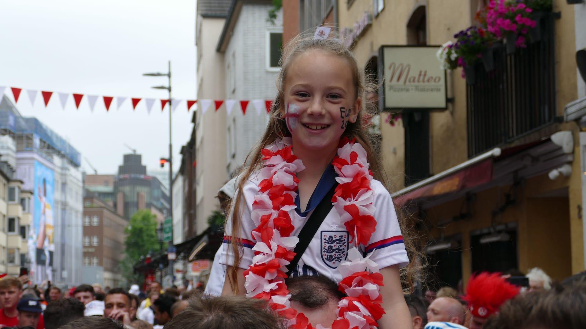 Englische Fans findet man am Samstagüberall in Düsseldorf: Dieses Mädchen hat wohl von den Schultern ihres Vaters die beste Sicht auf die feiernde Menge .