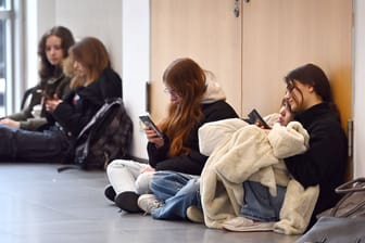 Schülerinnen gucken auf ihre Handys (Symbolbild): Der hohe Konsum wird von Experten als problematisch eingeschätzt.