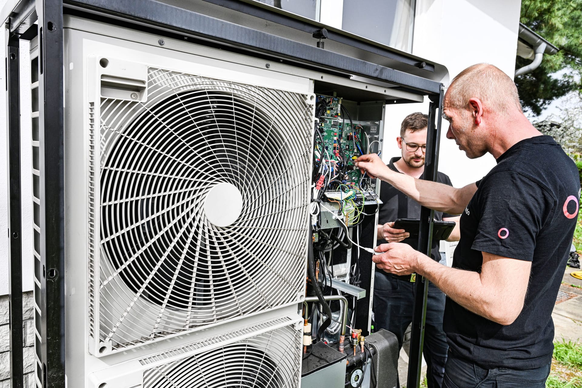 Techniker warten eine Wärmepumpe an einem Einfamilienhaus: Die Fördermittel für den Heizungstausch stehen ab August mehr Menschen offen.