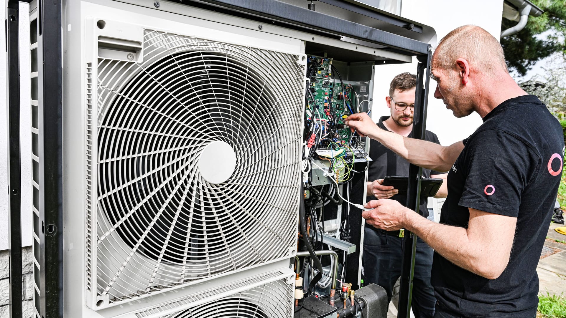 Techniker warten eine Wärmepumpe an einem Einfamilienhaus: Die Fördermittel für den Heizungstausch stehen ab August mehr Menschen offen.