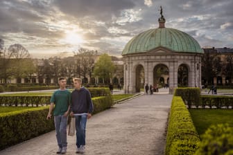 Two young friends are walking through Hofgarten, park in Munich