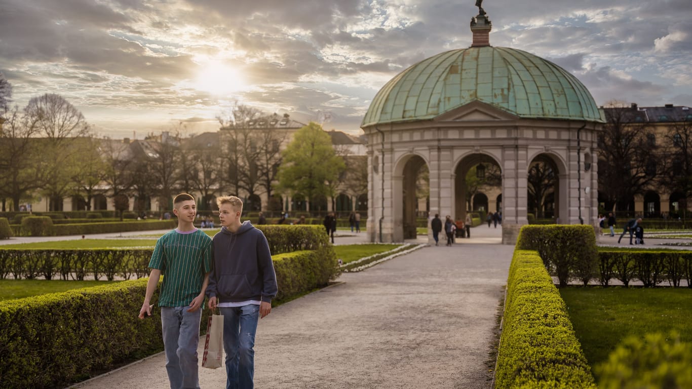 Two young friends are walking through Hofgarten, park in Munich