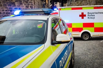 Ein Polizeiauto und ein Krankenwagen (Symbolbild): Bei der Fahrt verletzt der unbekannte Autofahrer zwei Menschen.