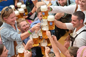 Menschen stoßen beim Oktoberfest mit Bier an (Archivbild): Ob der erneut gestiegene Maßpreis die Wiesnbesucher abschreckt, wird sich erst noch zeigen.