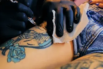 Close up image of making a tattoo on a woman's leg.